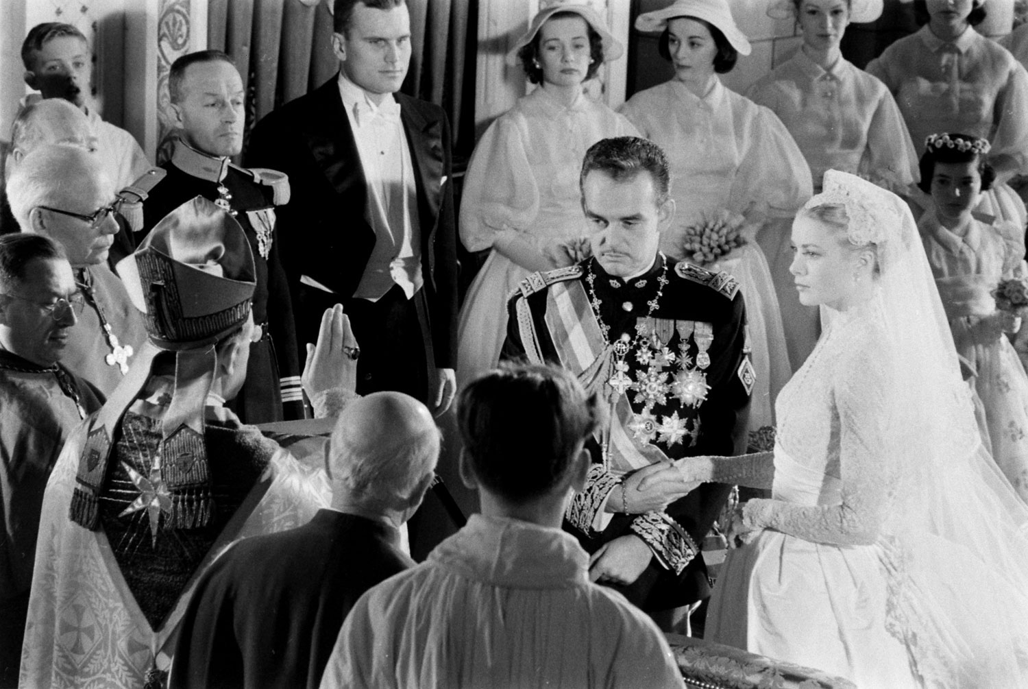 Grace Kelly and Prince Rainier join hands as the Bishop of Monaco, Mgr. Gilles Barthe, administers the nuptial benediction at Saint Nicholas Cathedral, April 1956.