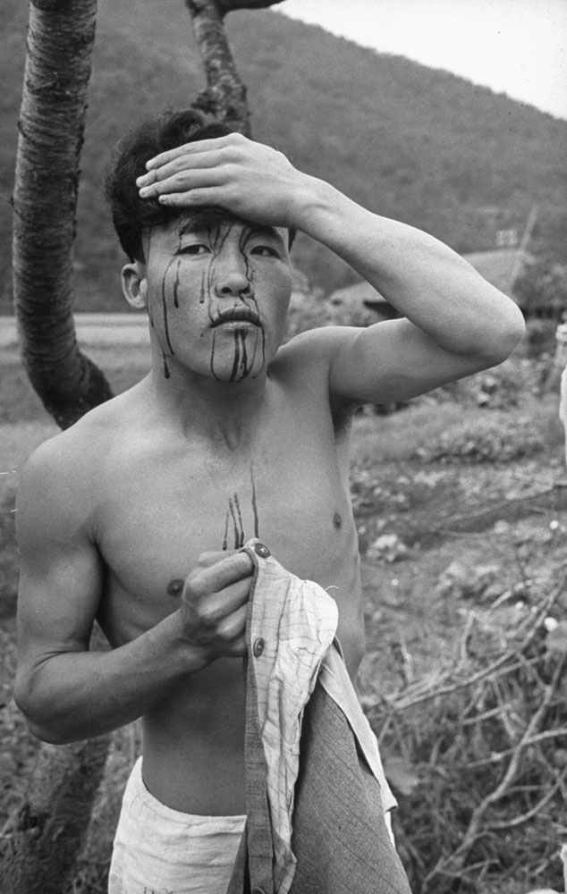 A civilian rebel holds his bloody head after 'questioning' by loyal soldiers who took Sunchon back from the revolting troops.