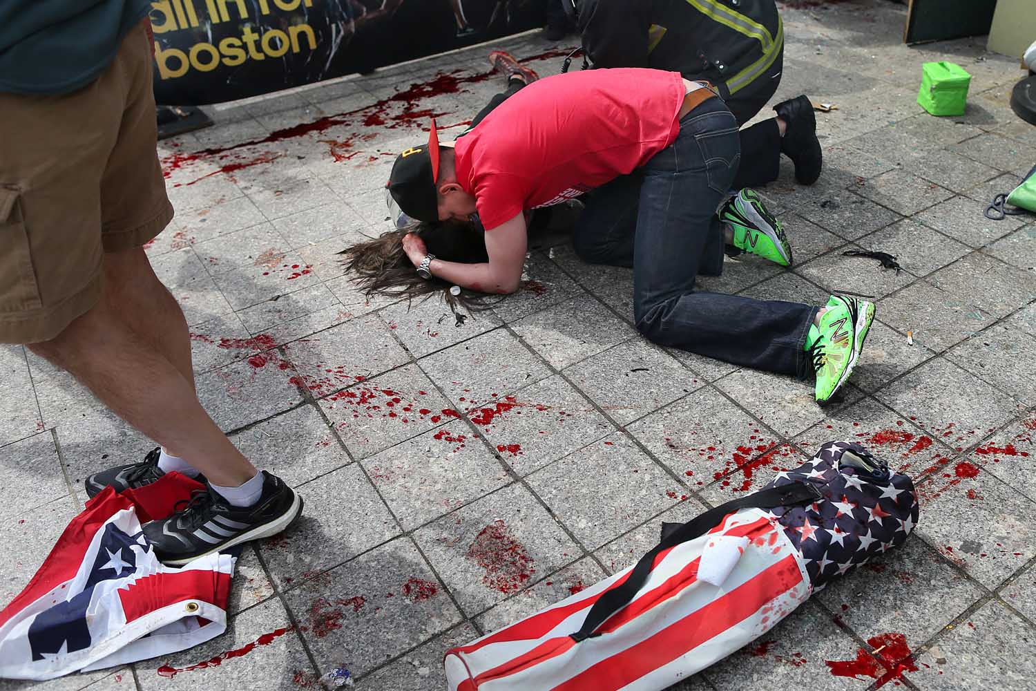 April 15, 2013. A man comforts a victim on the sidewalk at the scene of the first explosion near the finish line of the 117th Boston Marathon.