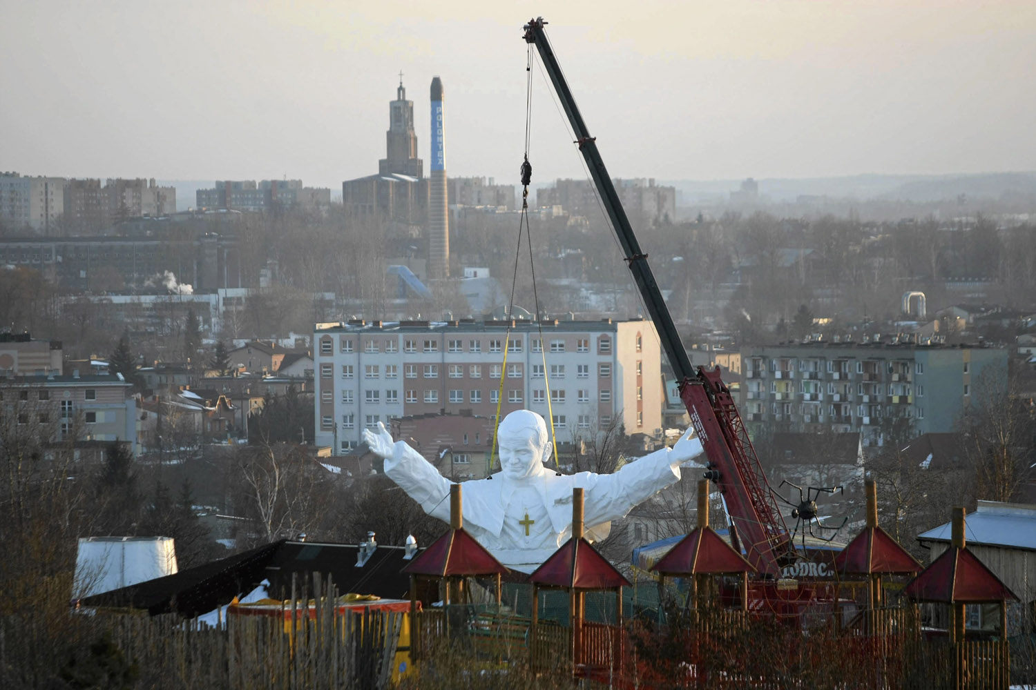 Monument to late Pope John Paul II is winched into position behind an amusement park in Czestochowa