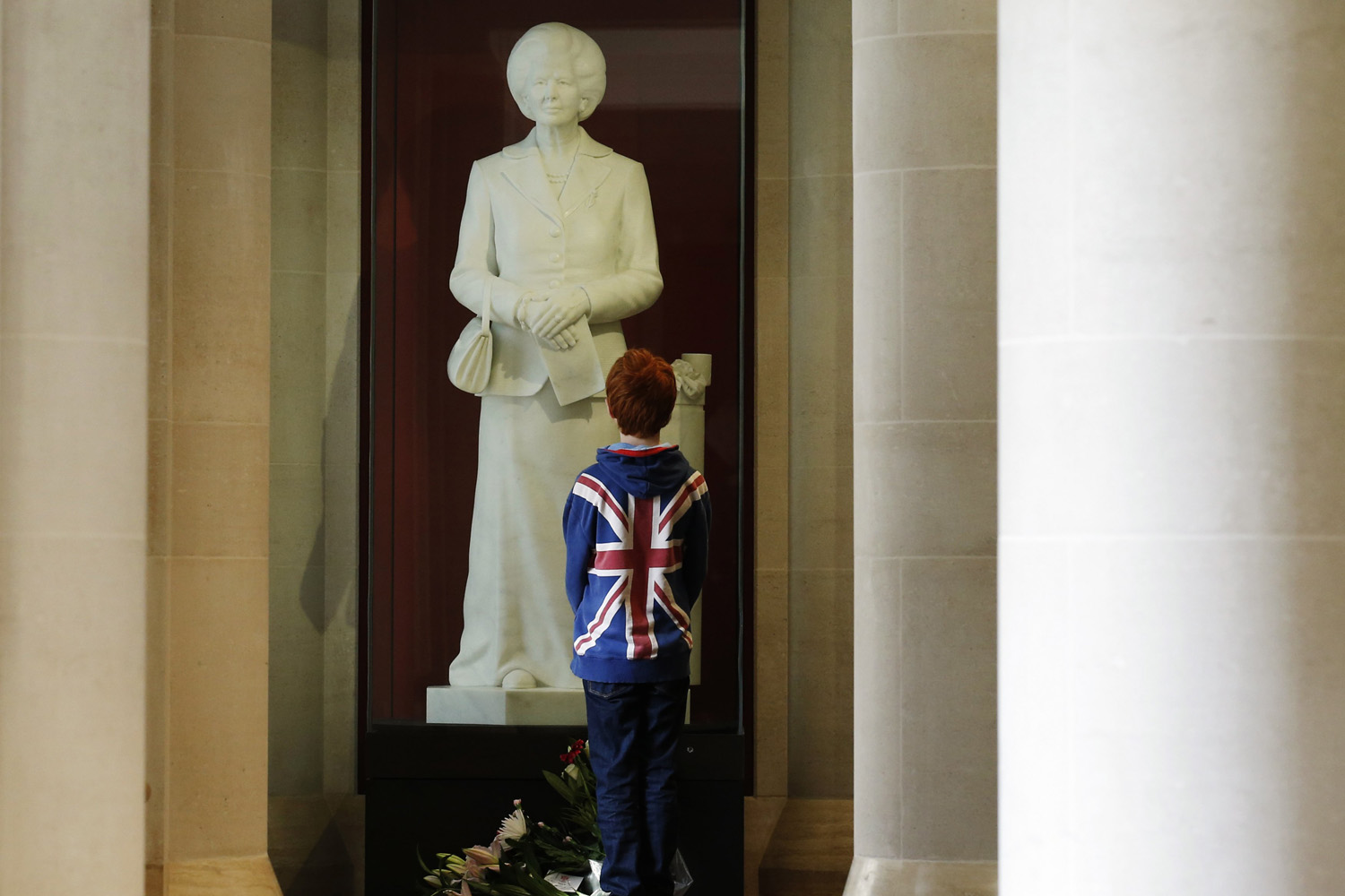 A boy stands in front of a statue of former British prime minister Margaret Thatcher by Neil Simmons, 2001, on display in the Guildhall Art Gallery in the city of London