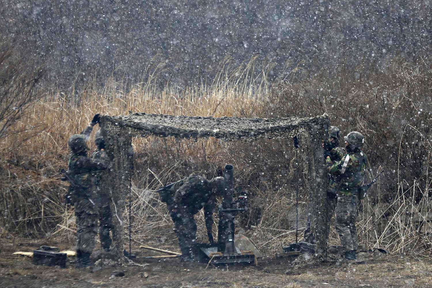 South Korean soldiers of an artillery unit check their gears during a drill as it snows in Hwacheon