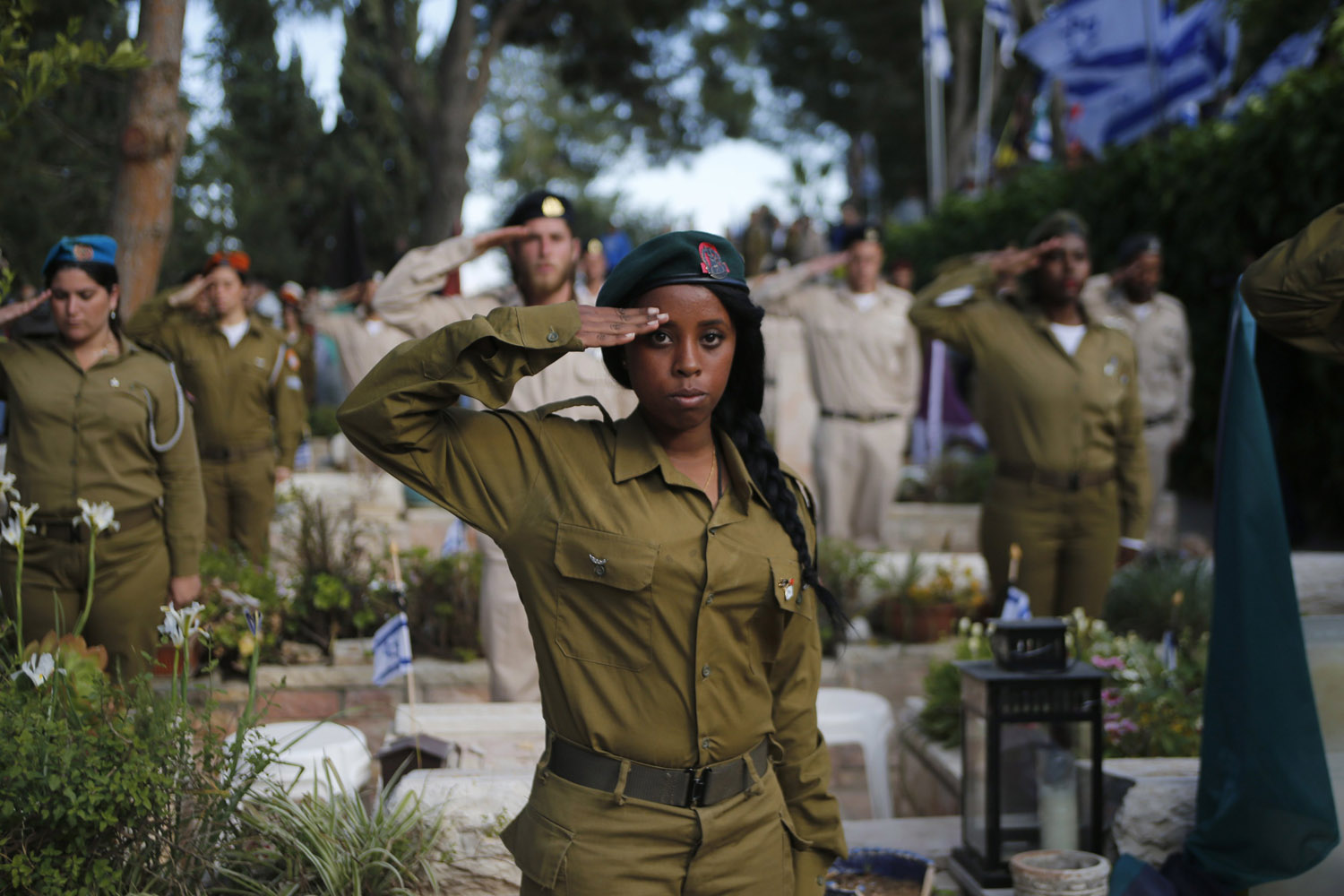 Israeli soldiers salute after placing flags on the graves of fallen soldiers at Mount Herzl military cemetery in Jerusalem