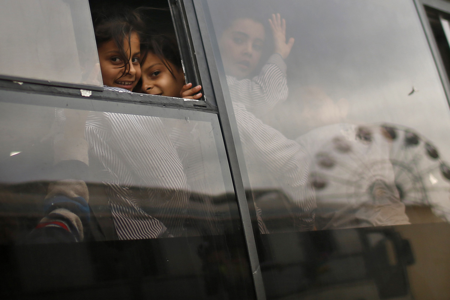 Palestinian school girls look through glass windows of a bus outside an amusement park built on a land of a former Israeli settlement in central Gaza Strip