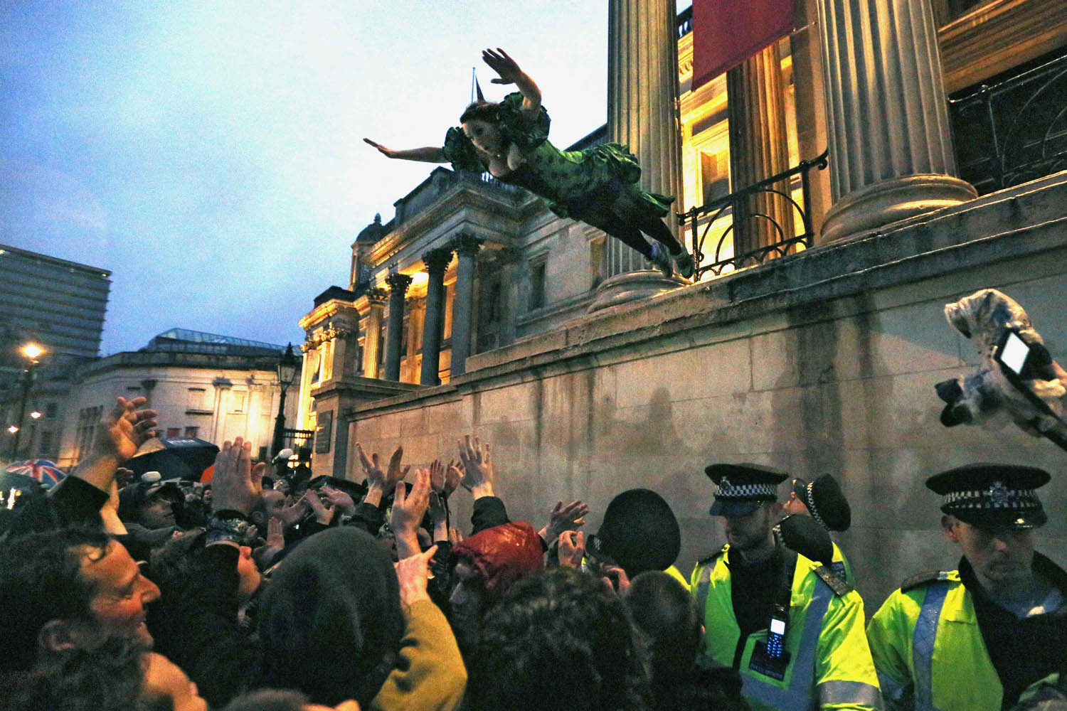 April 13, 2013. A reveller who had climbed onto a ledge outside the National Gallery leaps into the crowd during an outdoor party celebrating the death of former British Prime Minister Margaret Thatcher, at Trafalgar Square in central London.