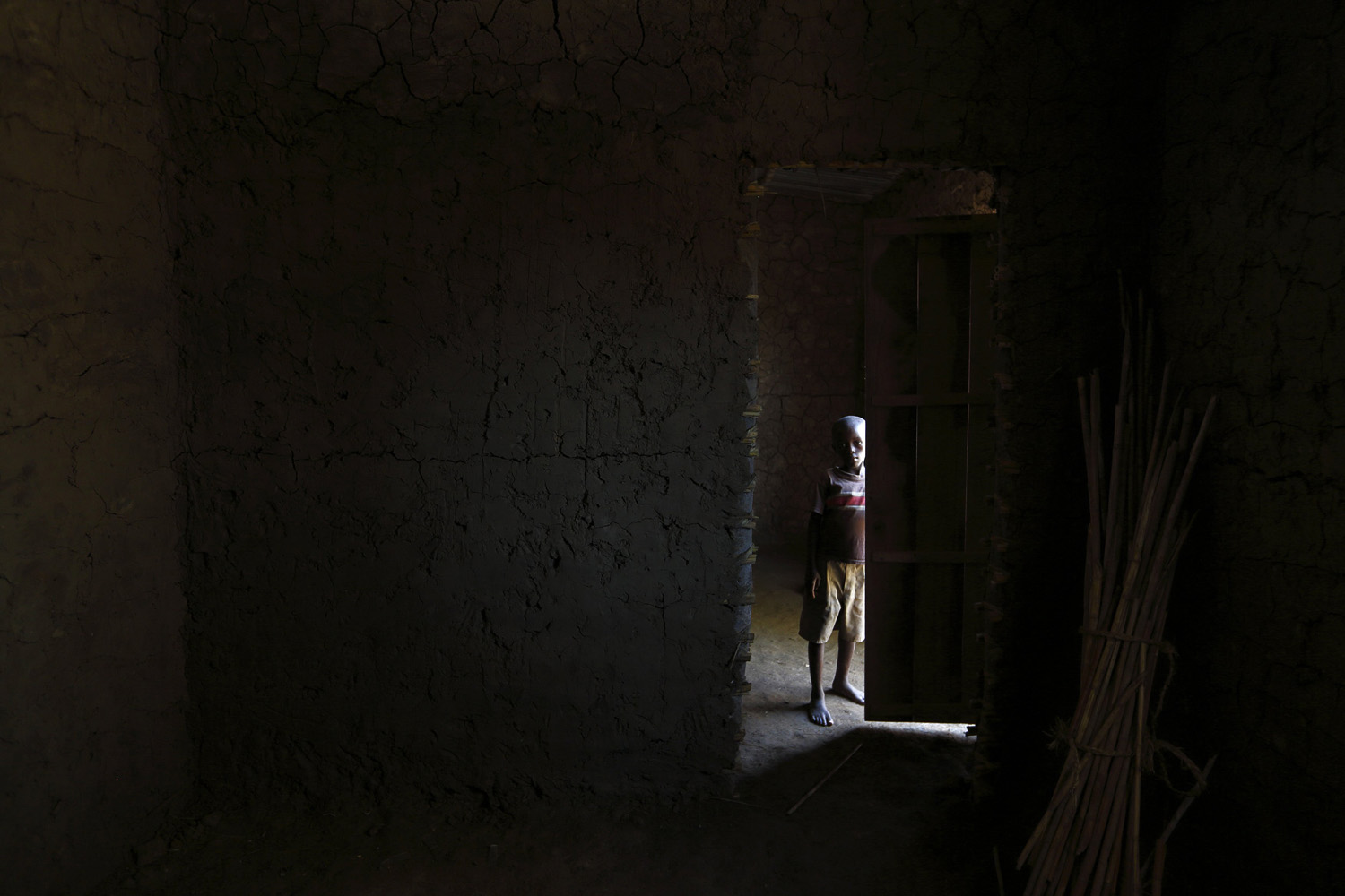 A child stands in the doorway of a mud-built house constructed by Service Yezu Mwiza for a widow it provides care for in Gatumba outside Bujumbura