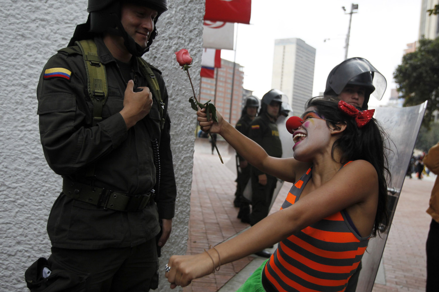 A student gestures with a flower to a policeman as she marches during the closing ceremony of the "Congress for Peace" in Bogota