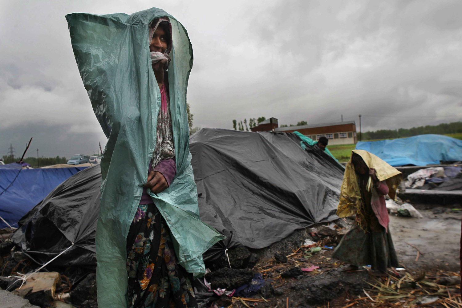 April 16, 2013. Two people living in a slum cover themselves in plastic sheets to protect themselves from the rain in Bijbehara, some 55 kilometres south of Srinagar, the summer capital of Indian-controlled Kashmir.