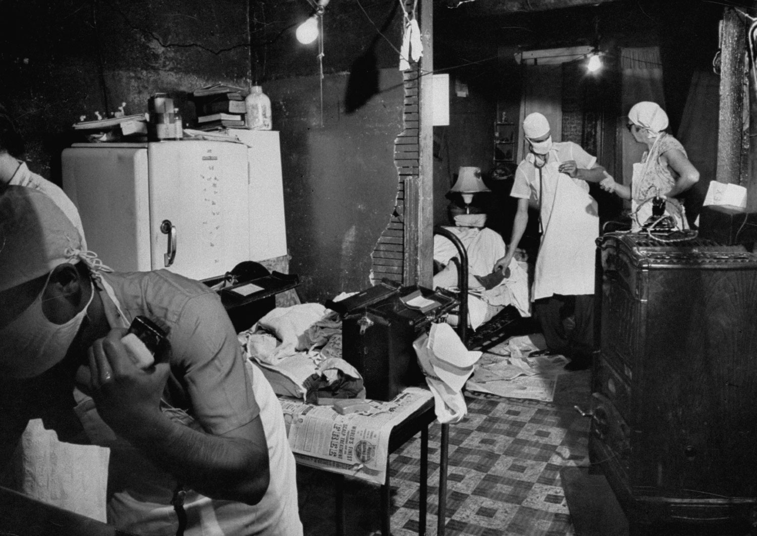 Intern and nurses from Chicago Maternity Center deliver a child in a squalid home, 1954.