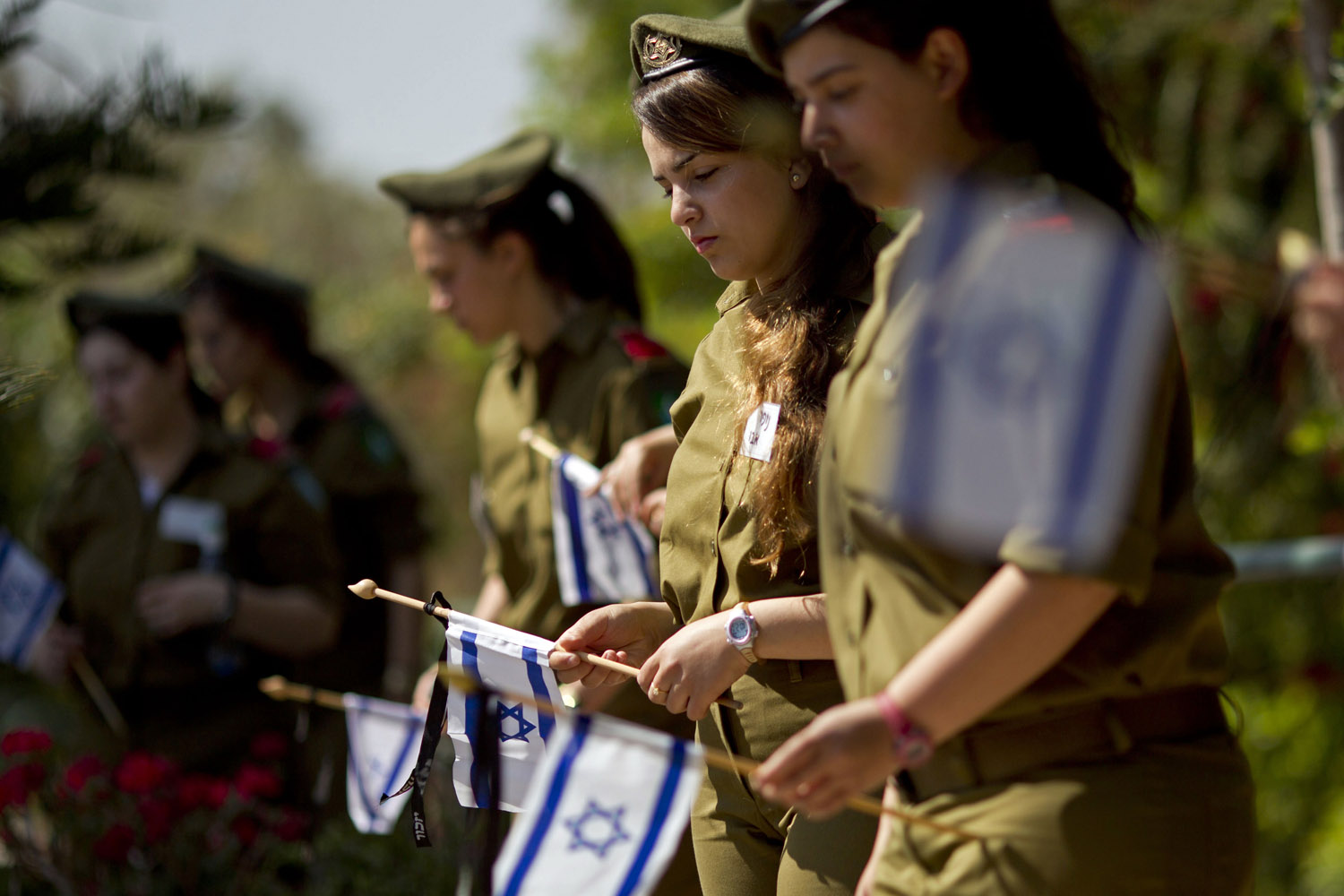 April 14, 2013. Israeli soldiers place Israeli flags with black ribbons on the graves of fallen soldiers at the Kiryat Shaul Military Cemetery in Tel Aviv.