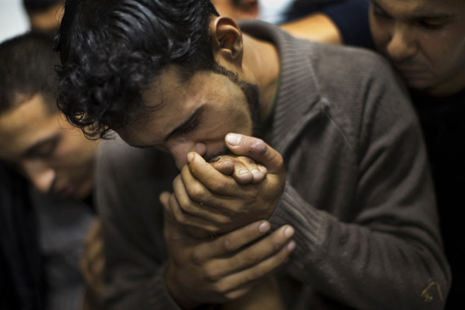 A Palestinian man kisses the hand of a dead relative in the morgue of Shifa Hospital in Gaza City, Nov. 18, 2012.