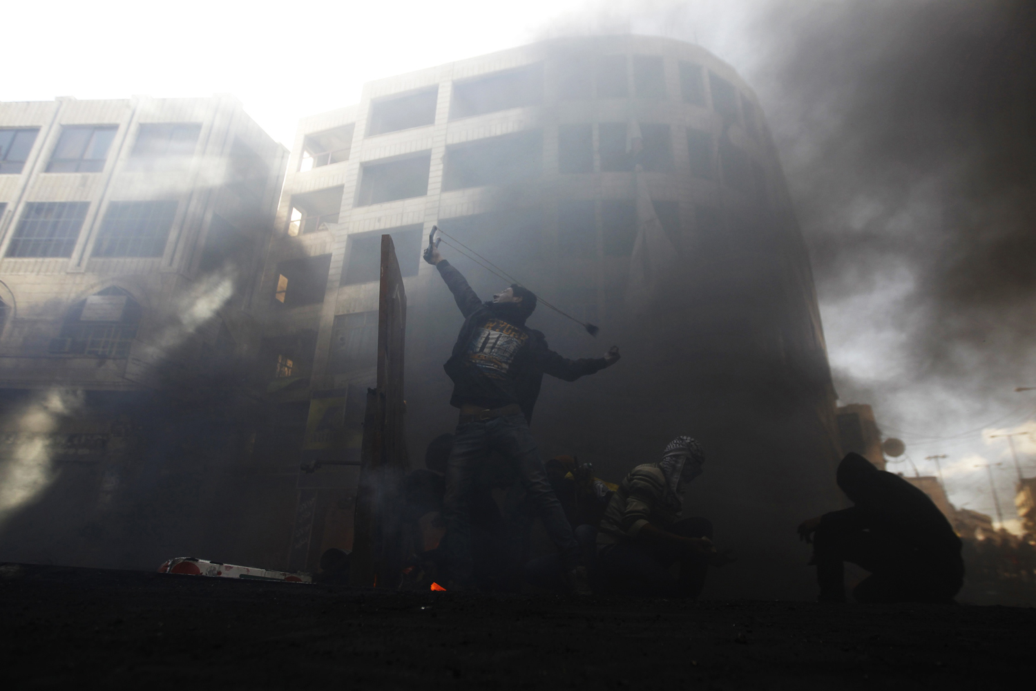 A Palestinian protester uses a sling shot to throw a stone during clashes with Israeli soldiers in Hebron