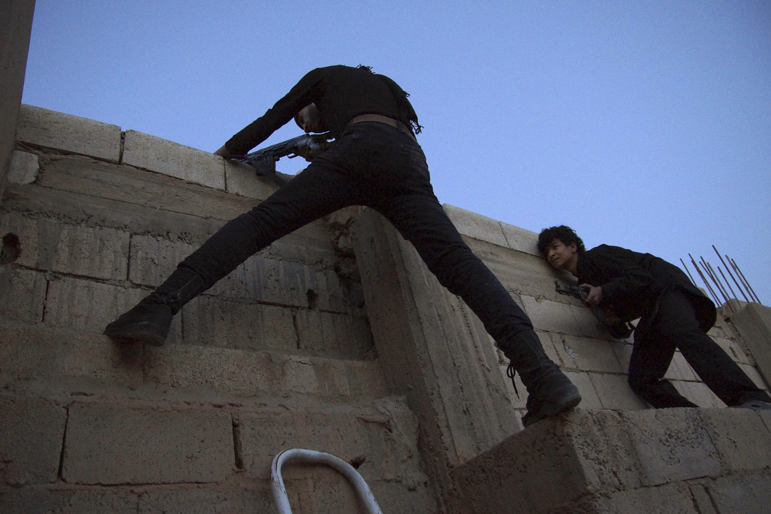 April 16, 2013. Free Syrian Army fighters take their position as one points his weapon from the top of a building in Deir al-Zor.