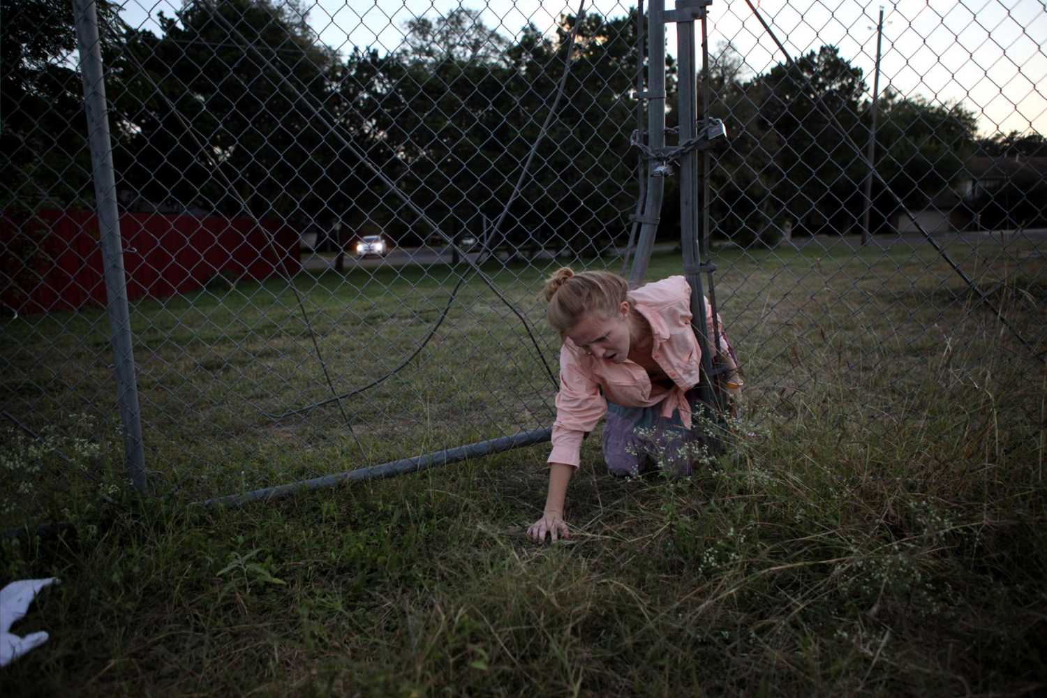 17 year old Anderson high school senior, Dandilion (Amy) Olson (pink shirt) crawls through a fence of the neighborhood church, a shortcut which avoids the long way around to the lake close to her house where she will go paddle-boarding with her sister and her sister's friend  on October 19, 2010.