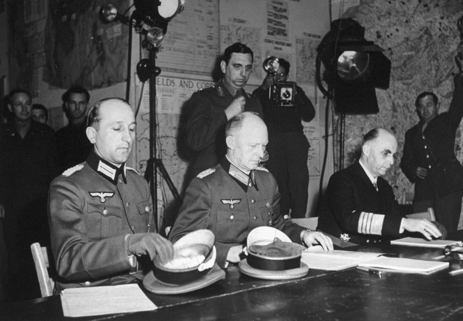Jodl, wearing Iron Cross low on his left breast, is seated between the major and admiral. With [German Head of State Karl] Donitz's authorization, he has nothing to do but sign the surrender.