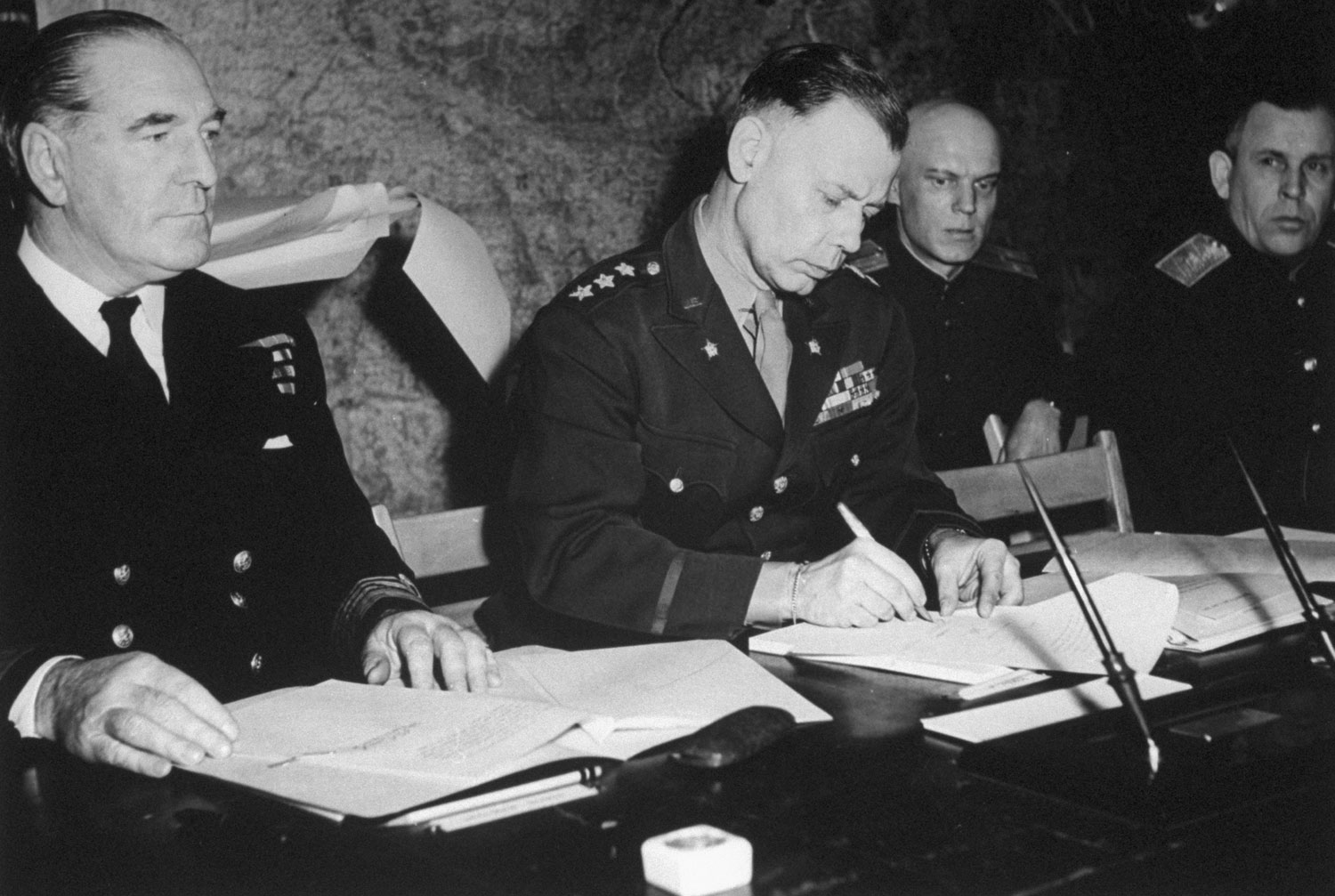 For Eisenhower, Chief of Staff Lieut. General Bedell Smith signs. At the left is Admiral Sir Harold Burrough, commander of Allied naval forces; right, Russian interpreter Cherniaeff.