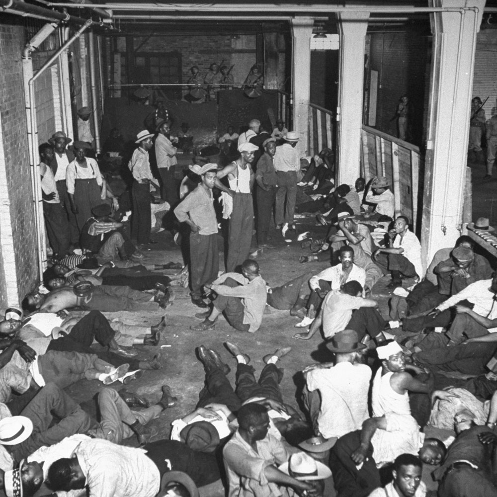 African American men rounded up under U.S. Army guard following wartime race riots in Detroit, June 1943.