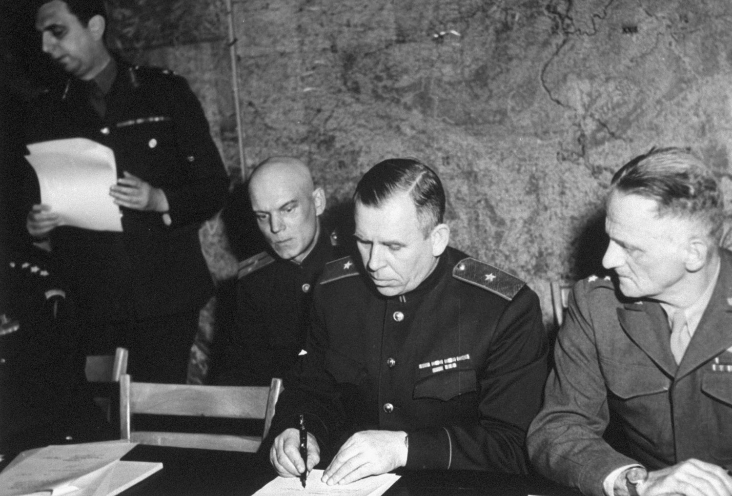 For Red high command, Major General Ivan Susloparov signs, to be followed by French General Francois Sevez for [Alphonse] Juin, commander of French expeditionary forces. At right, [American Gen. Carl Andrew] Spaatz.