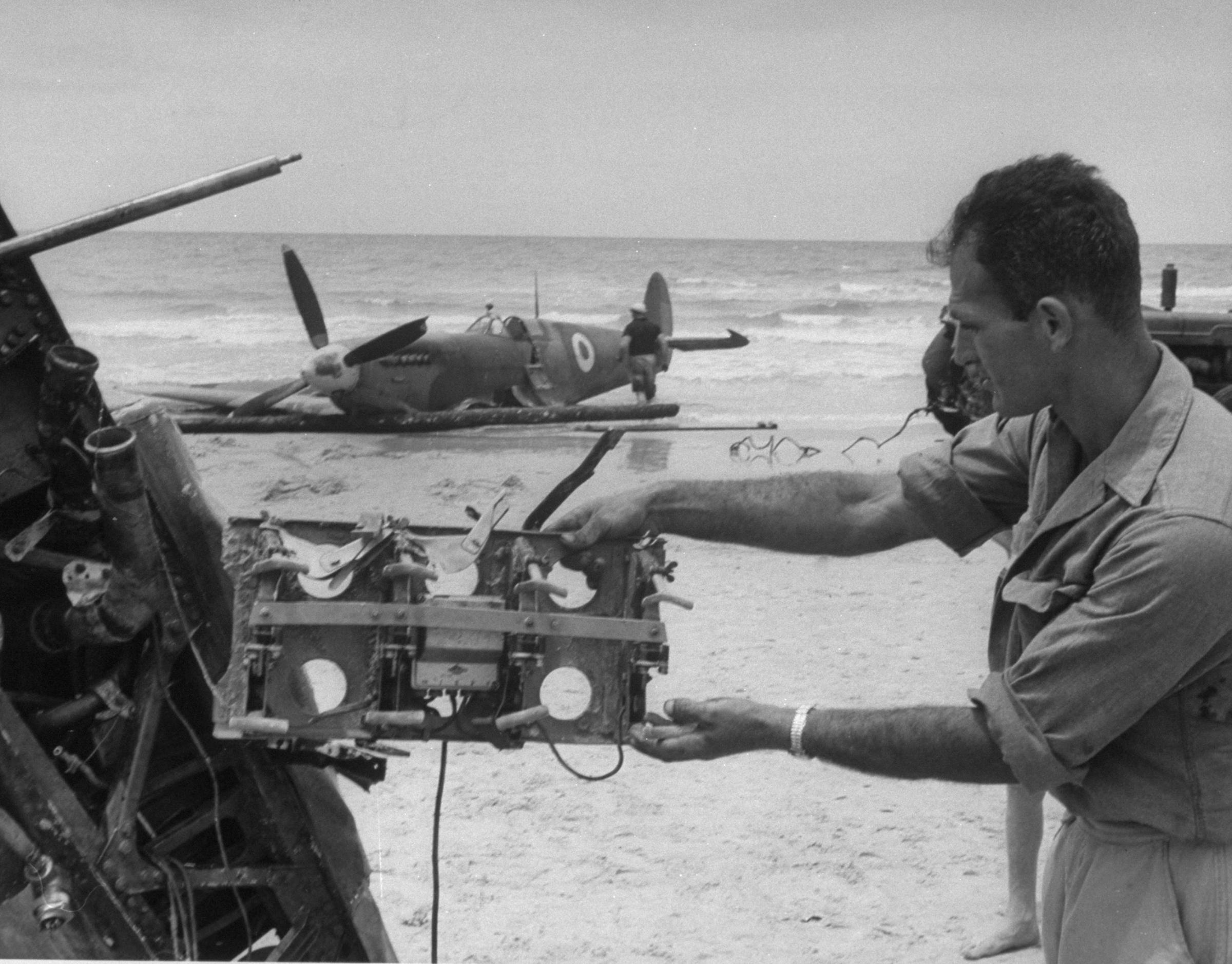 Haganah [Jewish paramilitary] soldier examines souvenir from Egyptian Spitfire shot down by Jews on Tel Aviv beach.