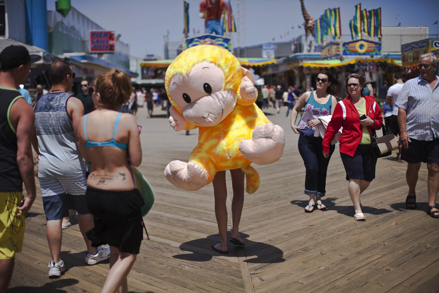 May 27, 2013. Nicole Zupp carries a stuffed monkey prize on the boardwalk at Seaside Heights on the first weekend of New Jersey beaches re-opening to the public.