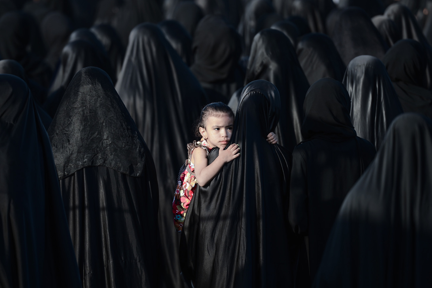 May 28, 2013. A Bahraini girl is carried by her mother during the funeral of Sayed Omran Sayed Hameed in the village of Karzakkan, south of Manama. Hameed, 26, died at hospital after developing respiratory complications and his relatives claim that his death is due to the inhalation of poisonous tear gas that riot police used during a protest in May of 2013.