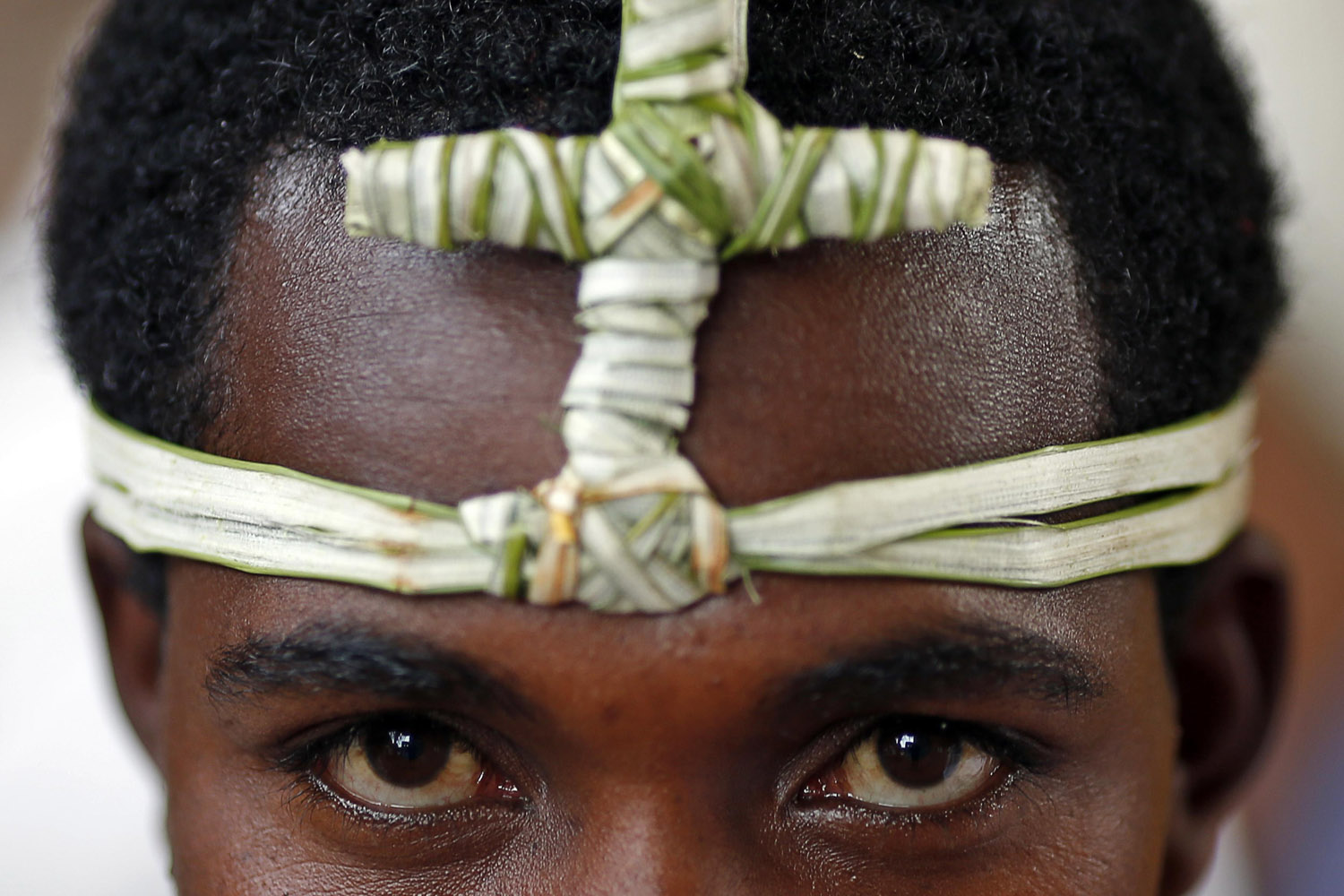 Orthodox Christians wears headband with cross made from papyrus as he prays outside of one of 11 monolithic rock-cut churches, in Lalibela