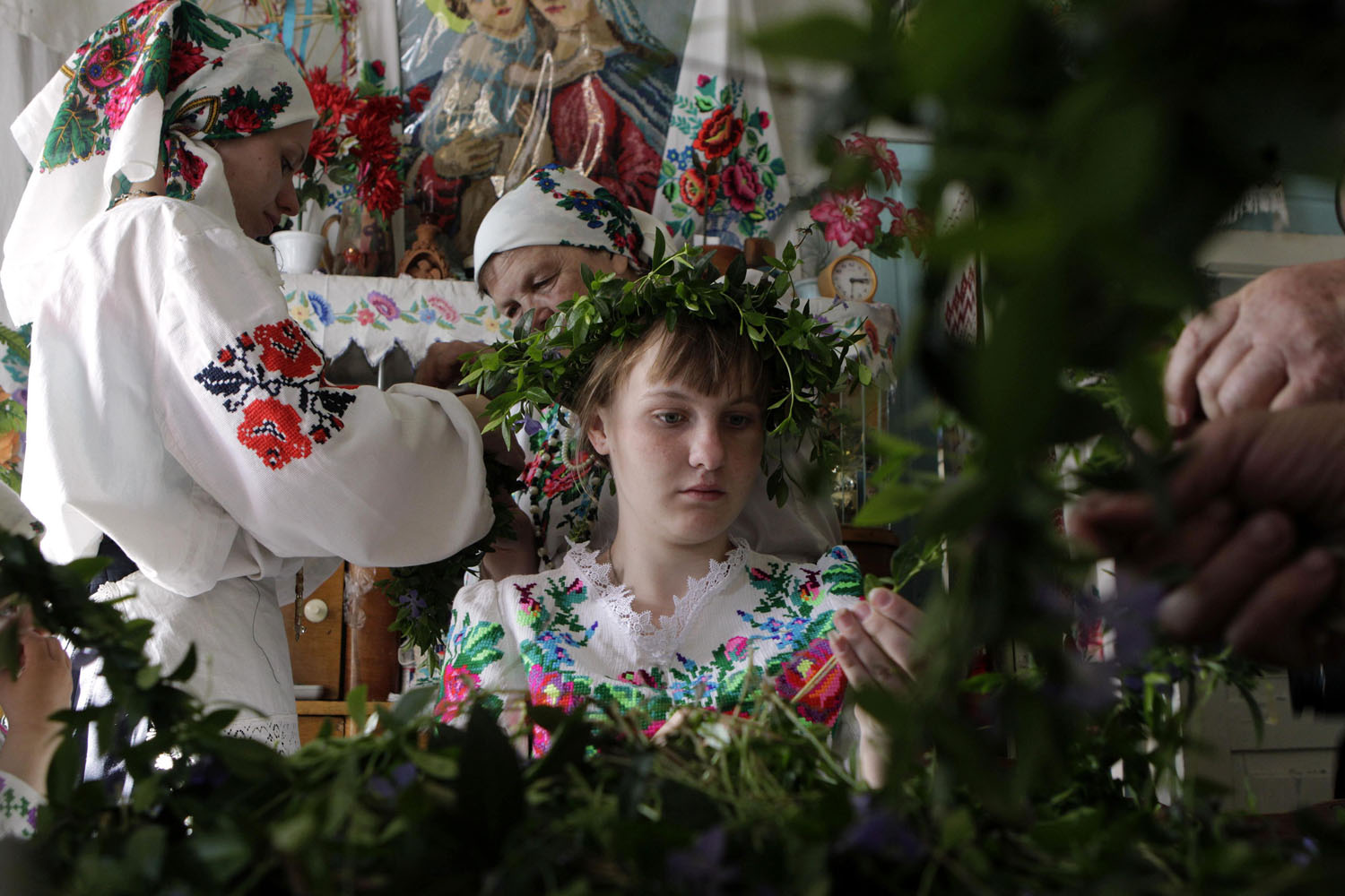 Women and girls in traditional dress make wreaths from periwinkle leaves to prepare for a ritual celebrating the pagan god Yurya in the village of Pogost