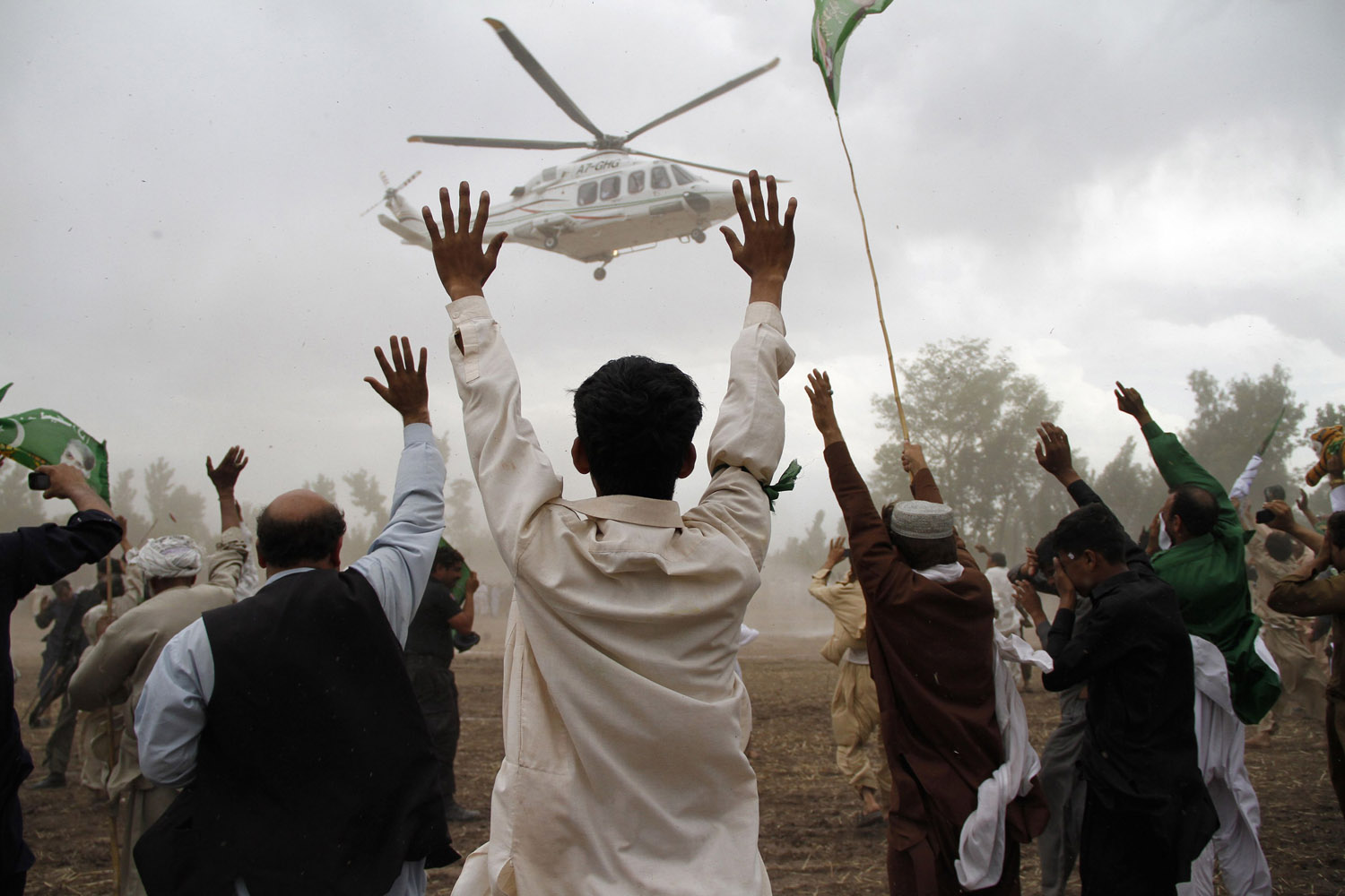 Supporters wave towards a helicopter transporting Sharif, leader of political party PML-N, as he leaves after his election campaign rally in Peshawar