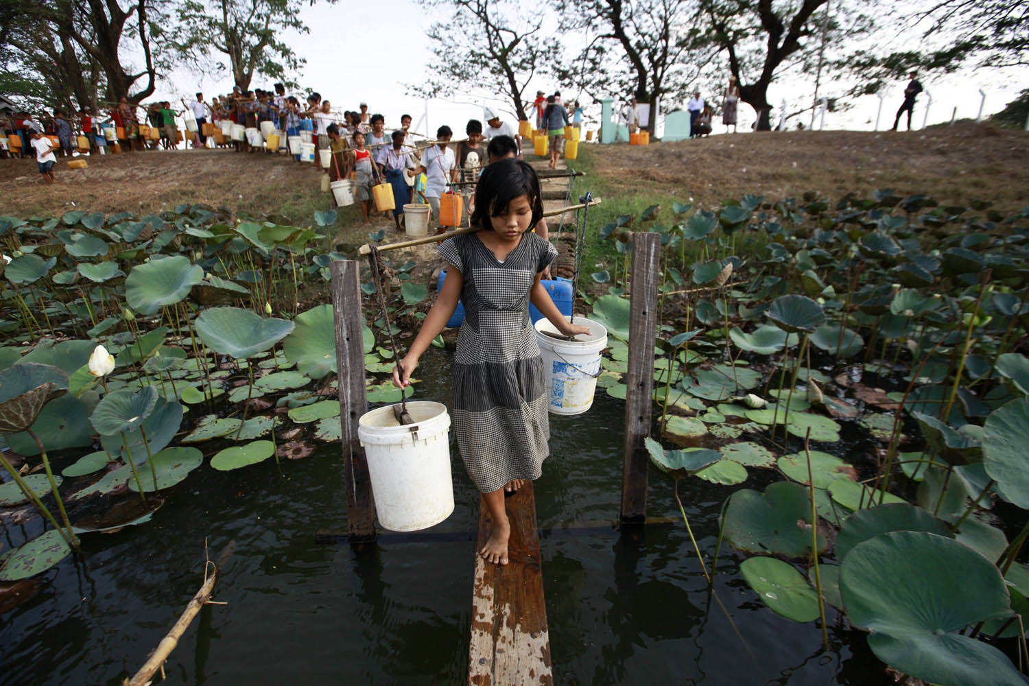 People line up to collect water at Yazarthingyan lake in Dala township, near Yangon