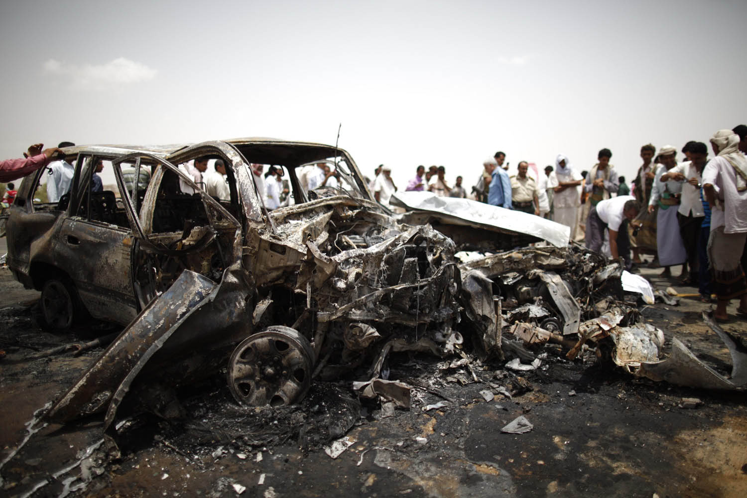 Policemen and people check the scene of a collision on a highway leading to a border crossing between Yemen and Saudi Arabia