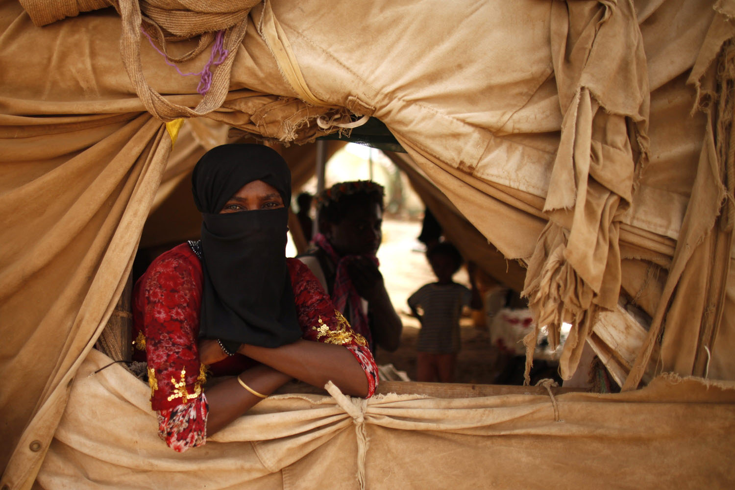 Woman looks from a window of her family's tent at a camp for internally displaced persons in al-Mazraq of the northwestern Yemeni province of Hajja