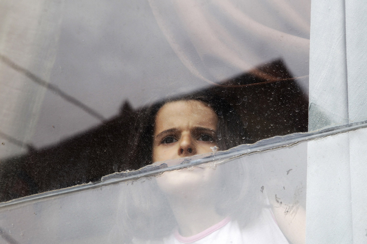 Koshi looks through the window of her house in the ethnically divided town of Mitrovica