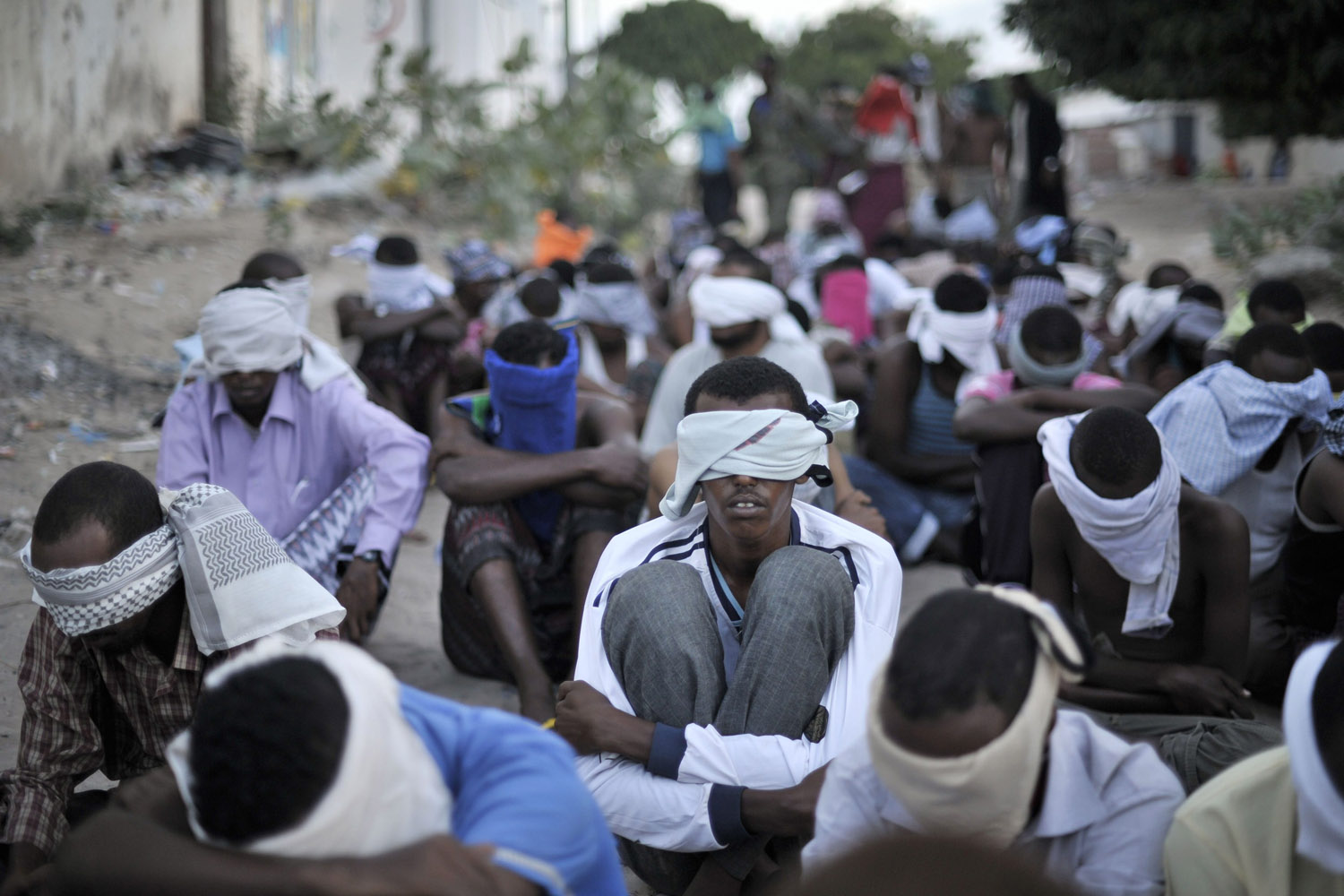 Men sit blindfolded after being rounded up by the Somali Police Force, to be screened during an operation aimed at improving security in Mogadishu