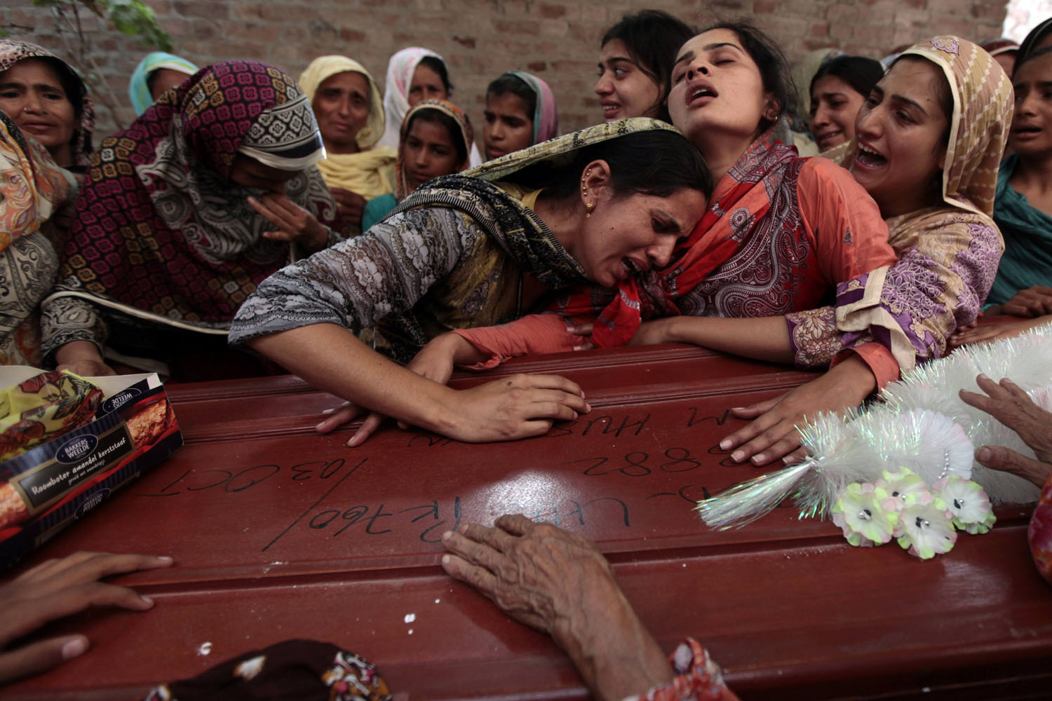 Relatives of one of seventeen children who died after a gas cylinder exploded on a school bus, mourn over his coffin, on the outskirts of Gujrat Southeast of Islamabad
