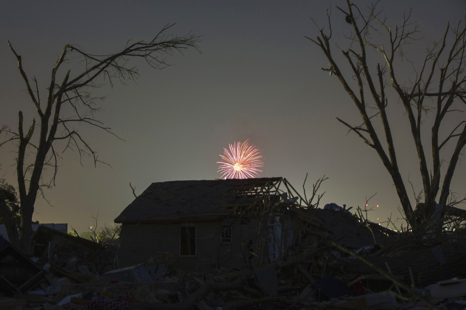Memorial day fireworks explode over a house damaged by the May 20 afternoon tornado in Moore, Oklahoma
