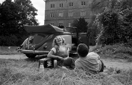 A young woman and man enjoy themselves beside a VW cabriolet, 1951.