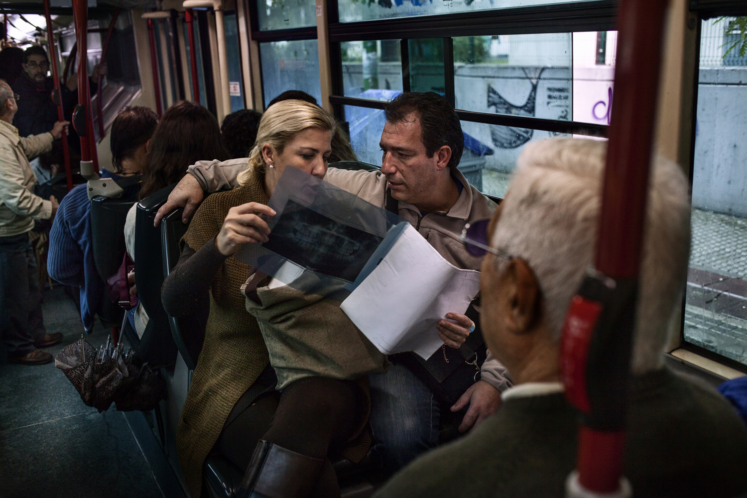 Noelia and Jaime, parents of triplets, look at an X-ray of Álvaro's mouth on the bus ride back home.