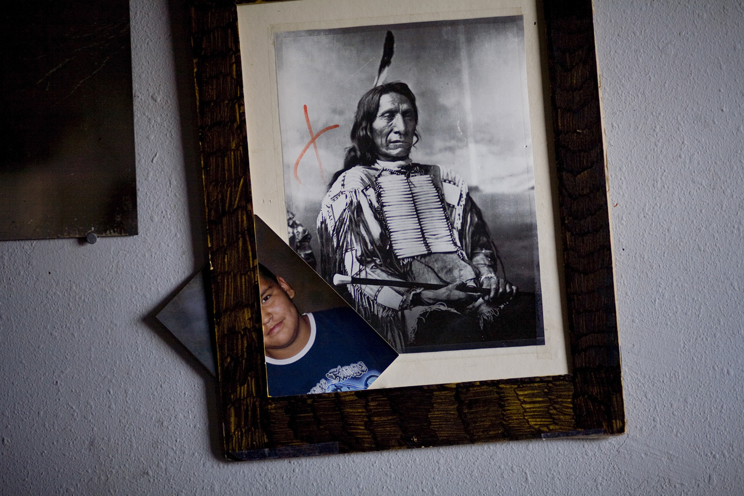 An old photograph of Chief Red Cloud hangs with a child's school picture in a house in Manderson.