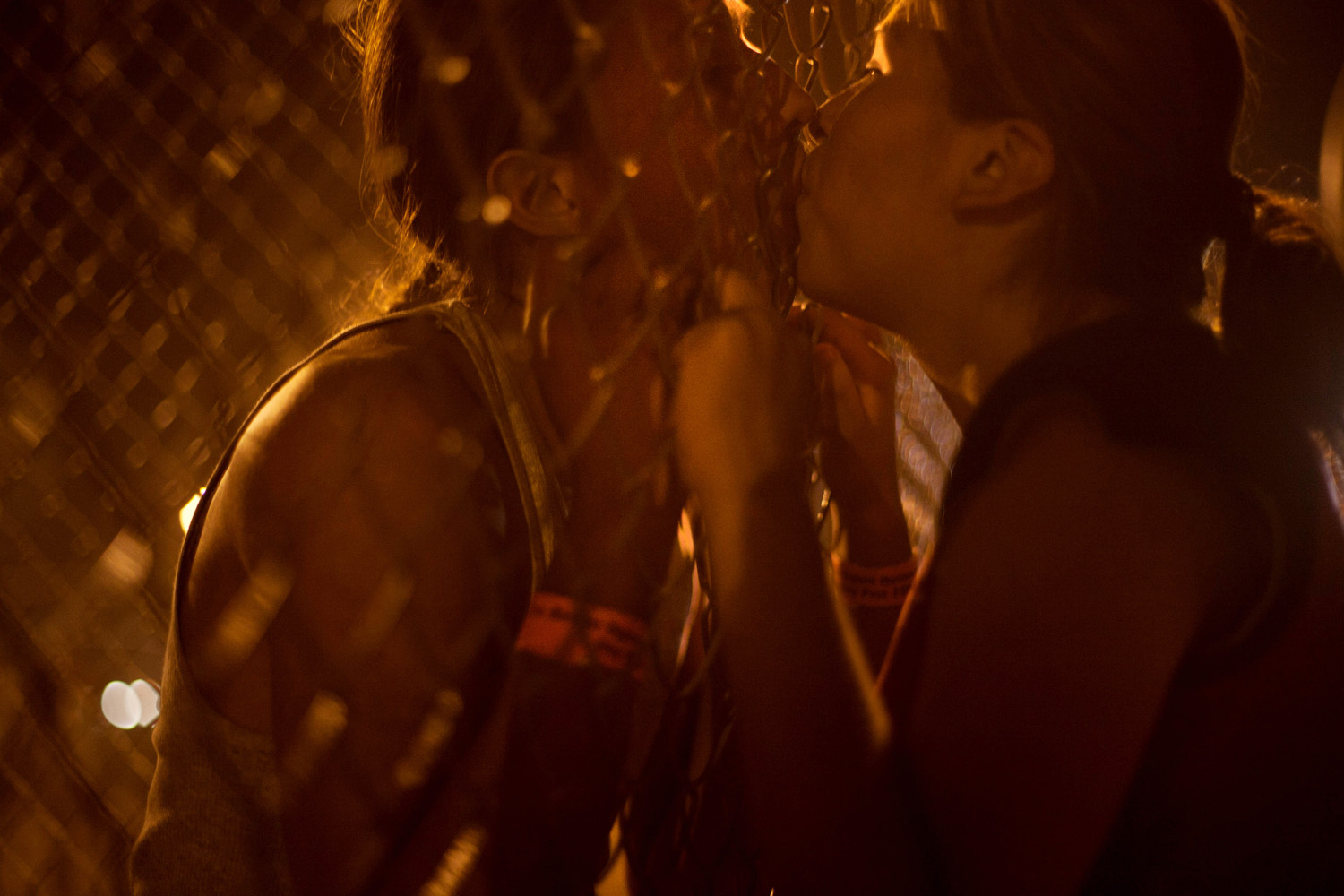 A young couple kissing through a fence at the Oglala Nation Pow Wow, Pine Ridge, SD.