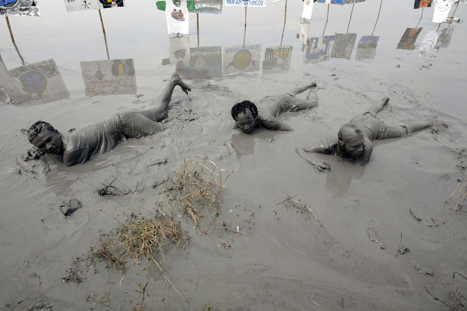 May 29, 2013. Displaced residents immerse themselves in massive mud deposits from the mud volcano in Sidoarjo village, located on Indonesia's eastern Java island to dramatize their sufferings during a protest marking the seventh year of the disaster.