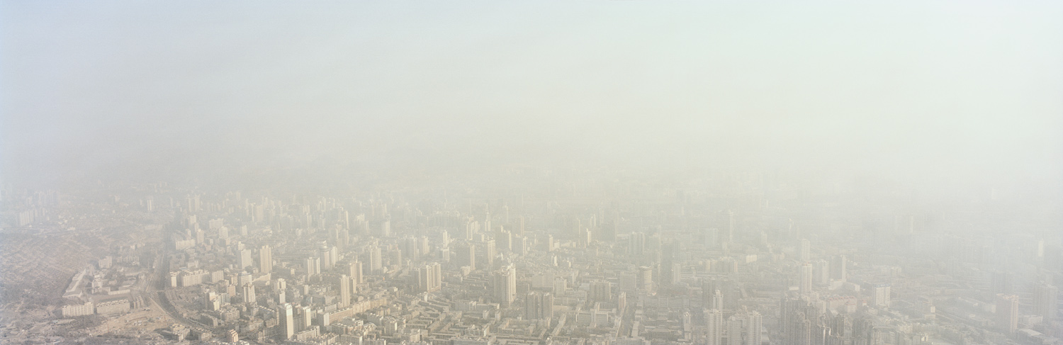 Cityscape. Lanzhou, Gansu, China, 2011. The expansive cityscape of Lanzhou cloaked in a polluted haze. Since 1949, the city, once a former Silk Road trading post, has morphed from the capital of a poverty-stricken province into the heart of a major industrial area. It is the center of the country’s petrochemical industry and is a key regional transport hub between eastern and western China. Among the country’s 660 cities, more than 400 lack sufficient water, while over 100 suffer from severe shortages. Lanzhou is the largest and first city on the Yellow River but is often better known for its massive discharge of industrial and human waste. According to recent reports by the Chinese government and international NGOs like the Blacksmith Institute, Lanzhou is China’s most polluted city and one of the 30 most polluted cities in the world.