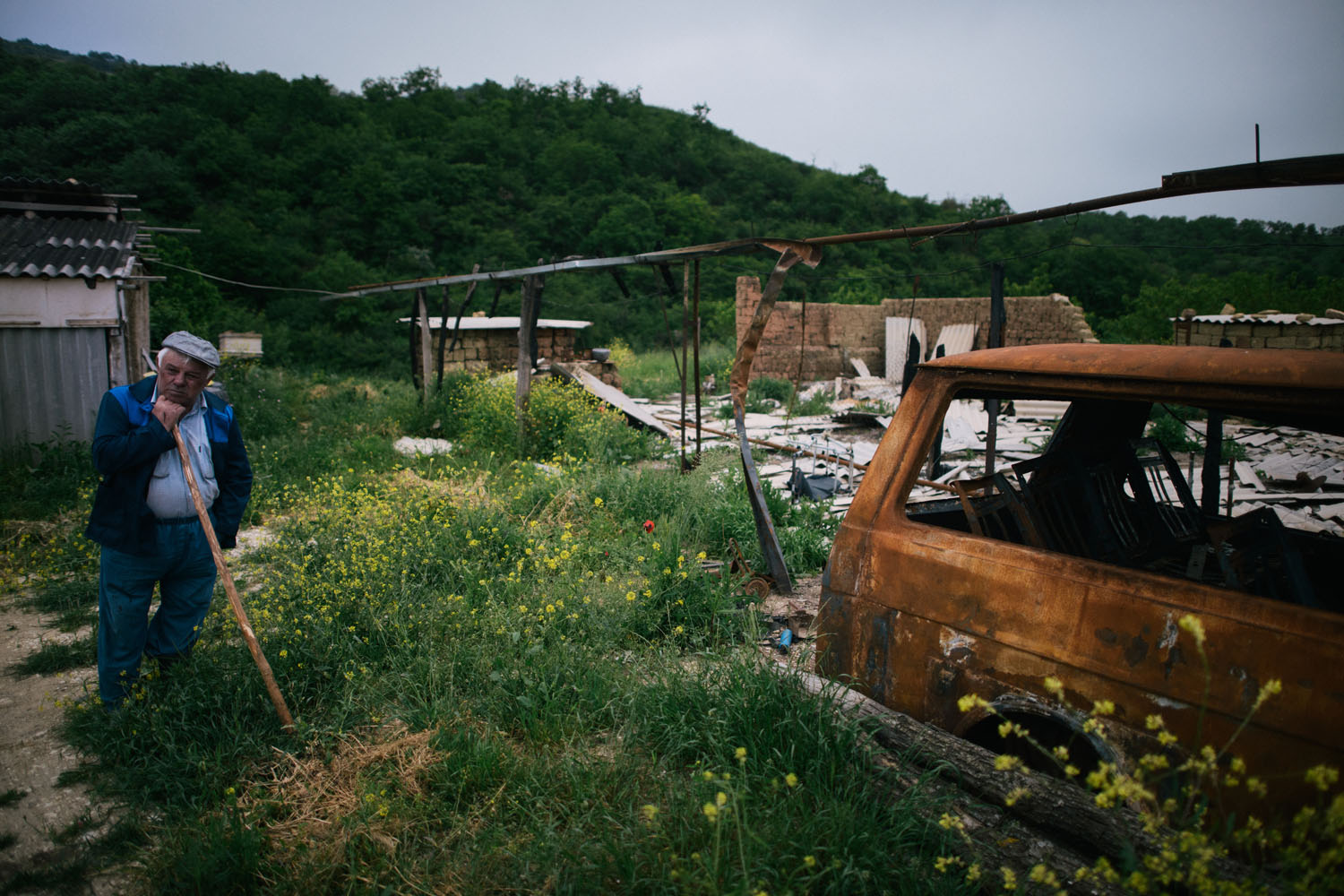 An owner of a farm  where William Plotnikov was killed with his friend stand near burned out buildings destroed during anti-terror operation near village Utamysh, where Plotnikov lived and died