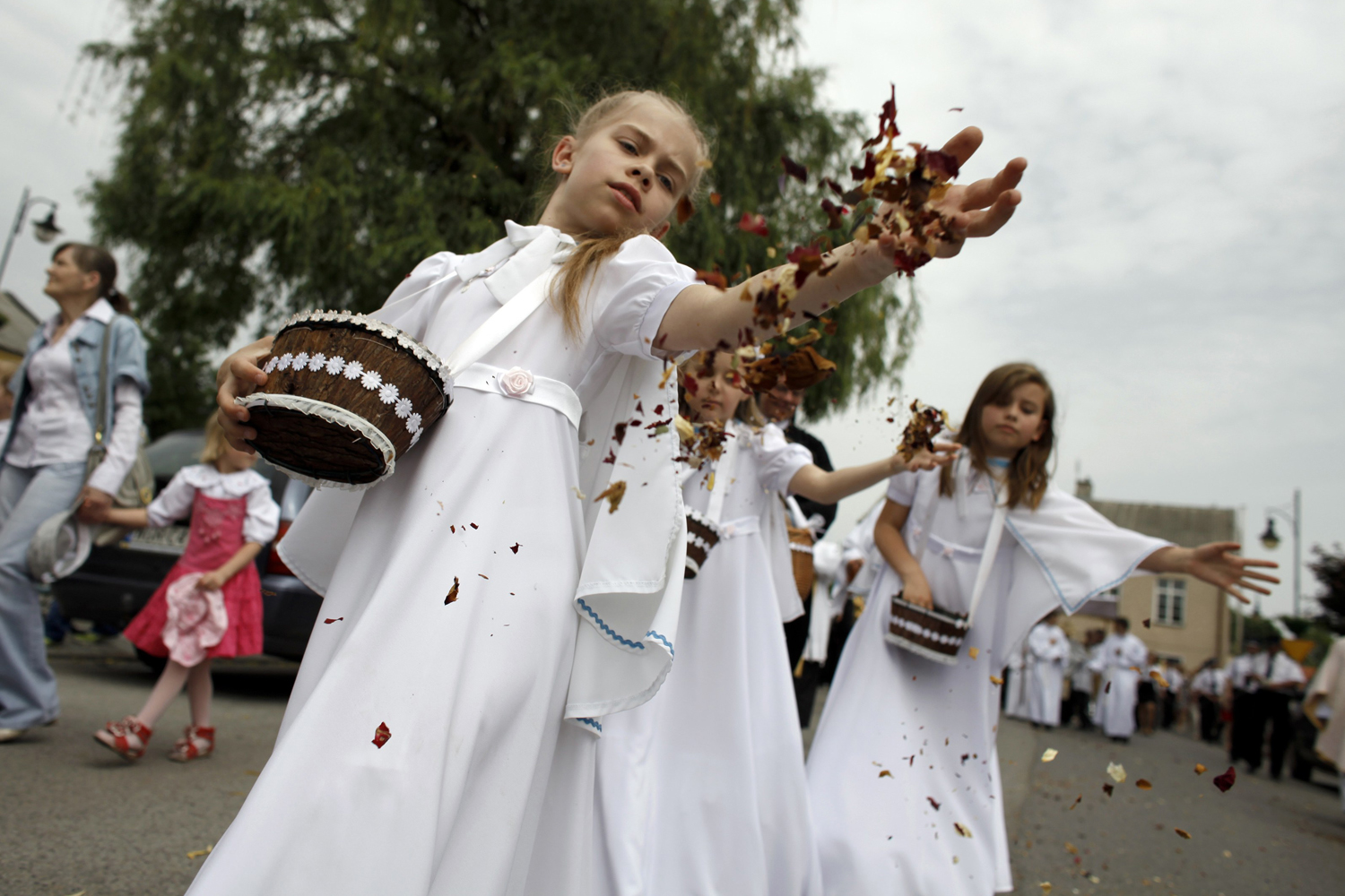 Girls throw flower petals before the Blessed Sacrament during a Corpus Christi procession in Gora Kalwaria