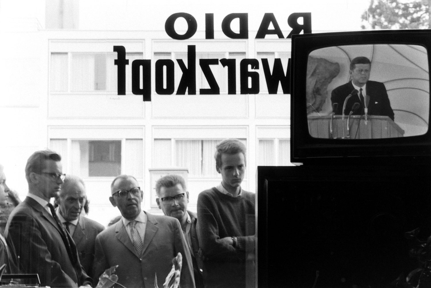 People watch and listen to John F. Kennedy on TV during his June 1963 visit to Germany.