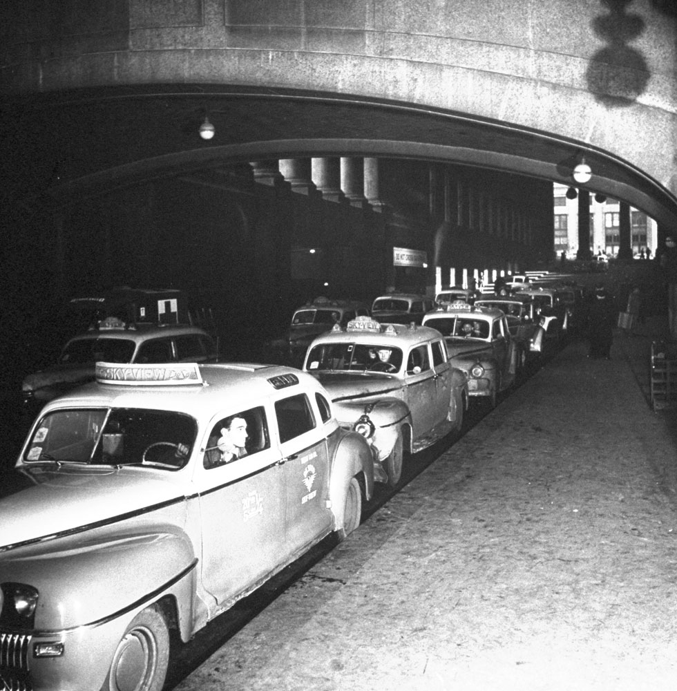 Taxicabs line up for arriving train passengers at (the original) Pennsylvania Station, New York City, 1944.