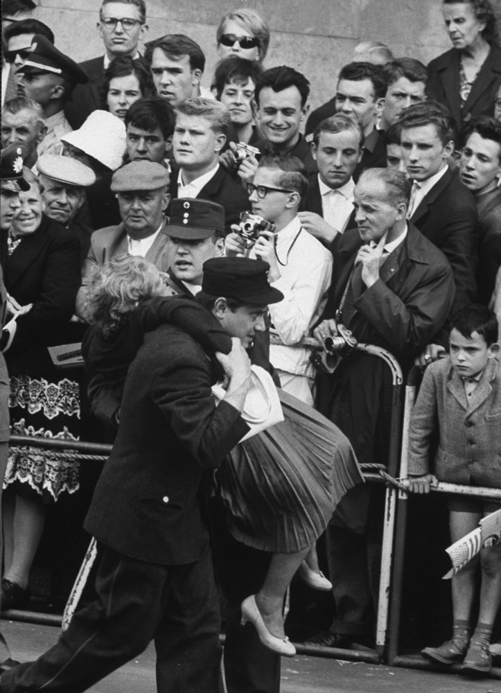 Fainting woman carried by Red Cross workers during commotion caused by President Kennedy's June 1963 visit to Germany.