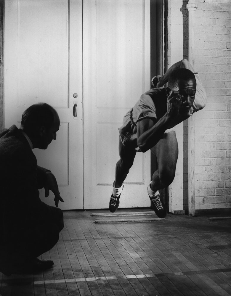 Hurdler Harrison Dillard beginning a sprint as his coach watches, 1948.