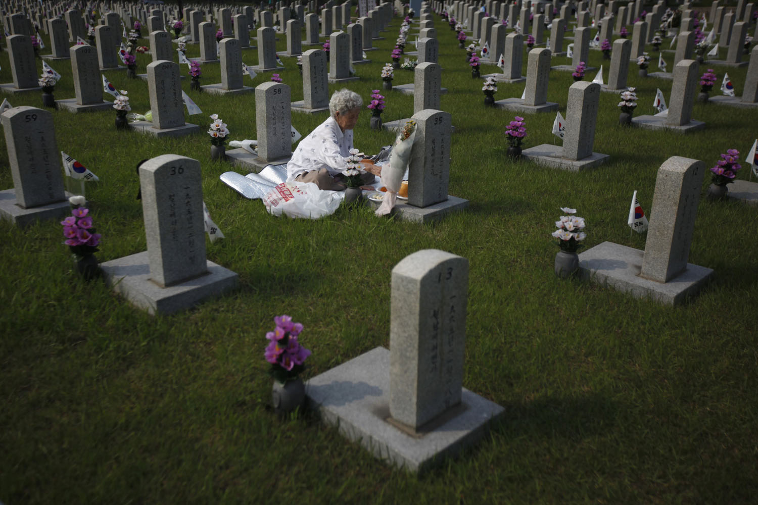 Woman pays her respects in front of the gravestone of her son who died for the country, at the national cemetery in Seoul