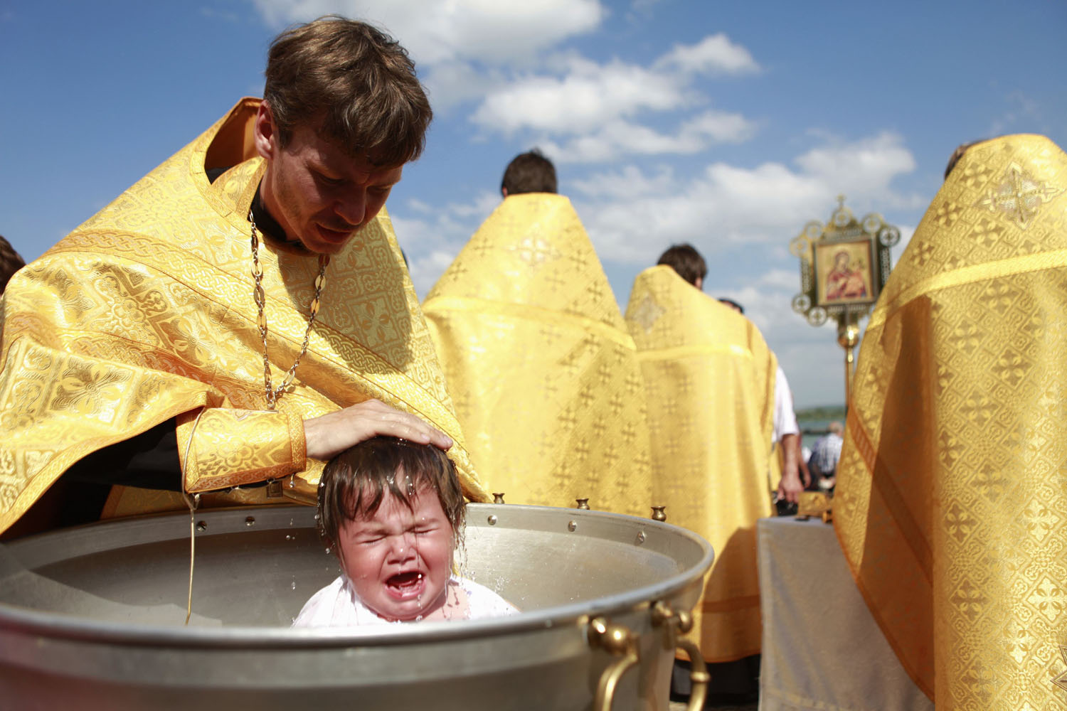 A priest baptises a child at Novopyatigorsk lake near Pyatigorsk