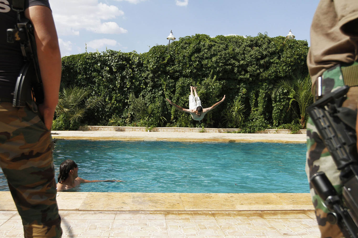 A member of the Free Syrian Army dives into a swimming pool in Aleppo